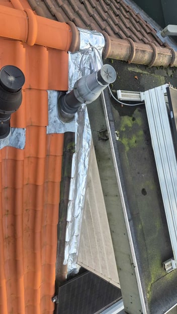 Tijdelijke afdichting met tape over dakkapellood als noodoplossing bij een daklekkage.