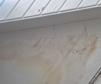 Vochtplekken en verkleuringen op een plafond als eerste zichtbare signalen van dakproblemen binnenshuis.