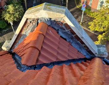 Lekkende aansluiting tussen dak en gevel met beschadigde loodslab