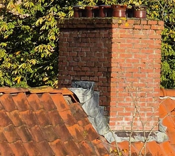 Schoorsteen met verouderde loodslabben en verhoogd lekkagerisico