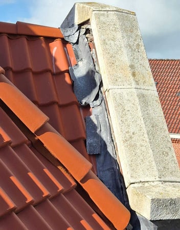 Lekkende aansluiting tussen dak en gevel met beschadigde loodslab